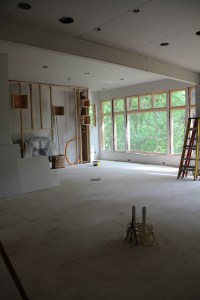 A view from the future kitchen to the fireplace wall and great room window.  Those pipes in the foreground are where the island and sink will be.